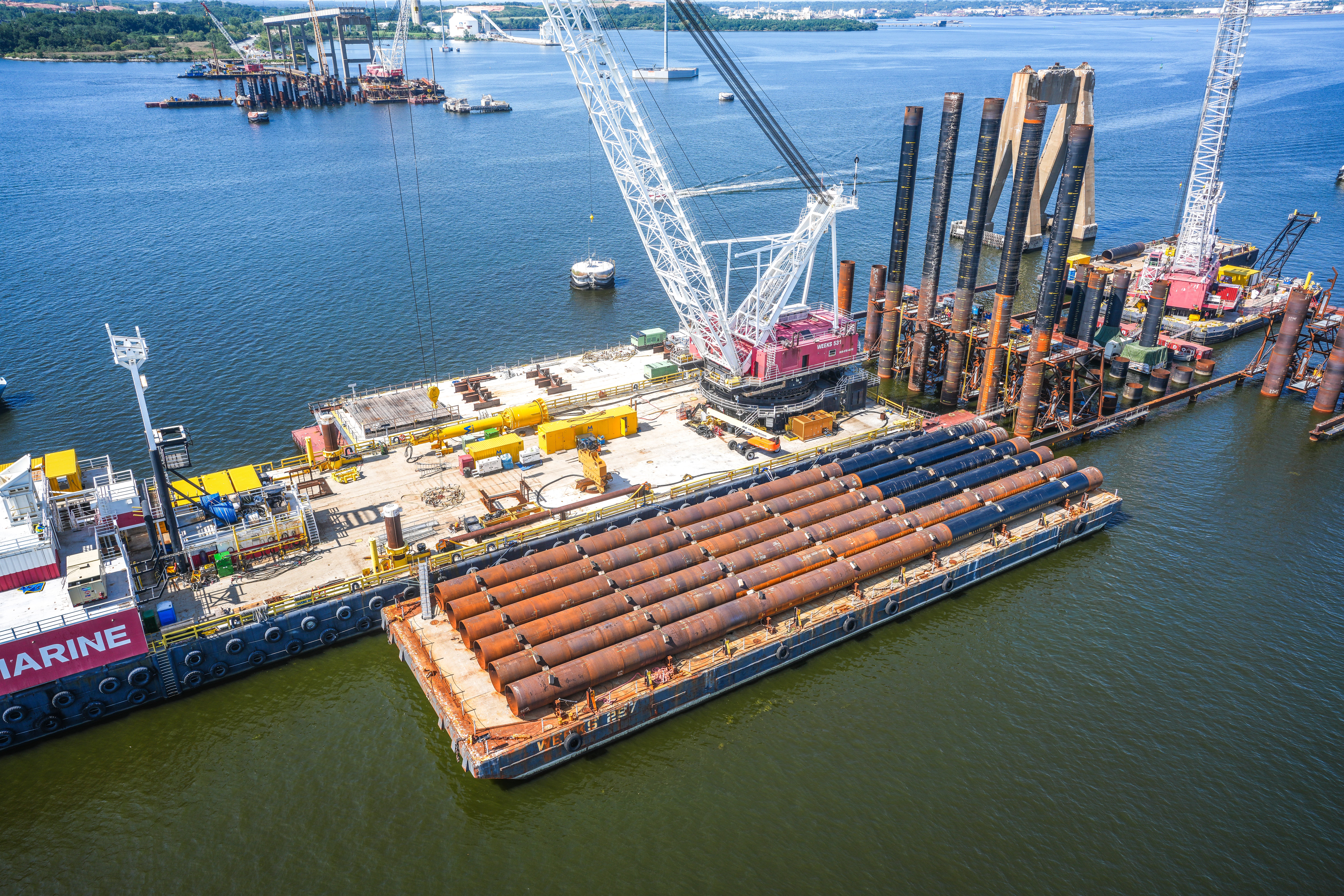 Aerial view of barge on water with cranes and bridge piles.