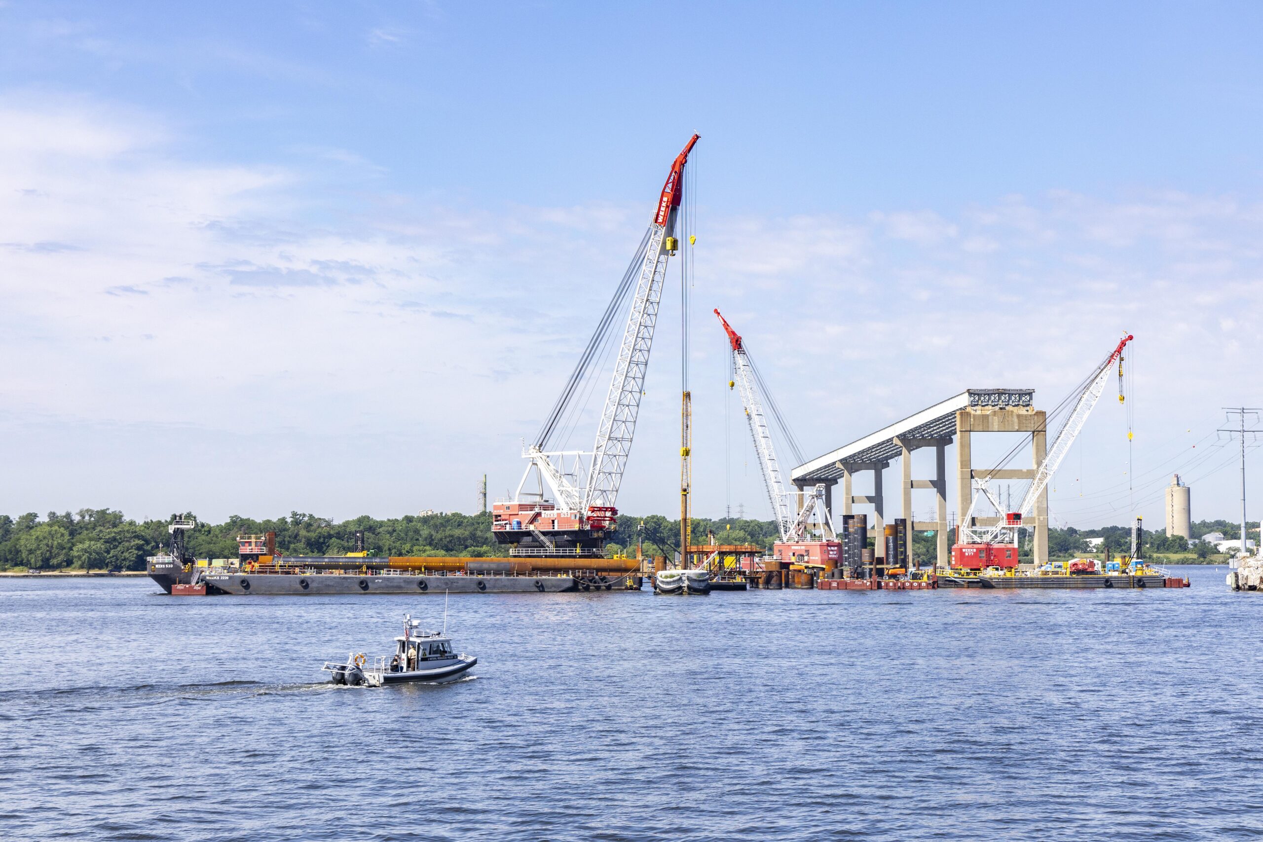 Image of boat on water with cranes in background.