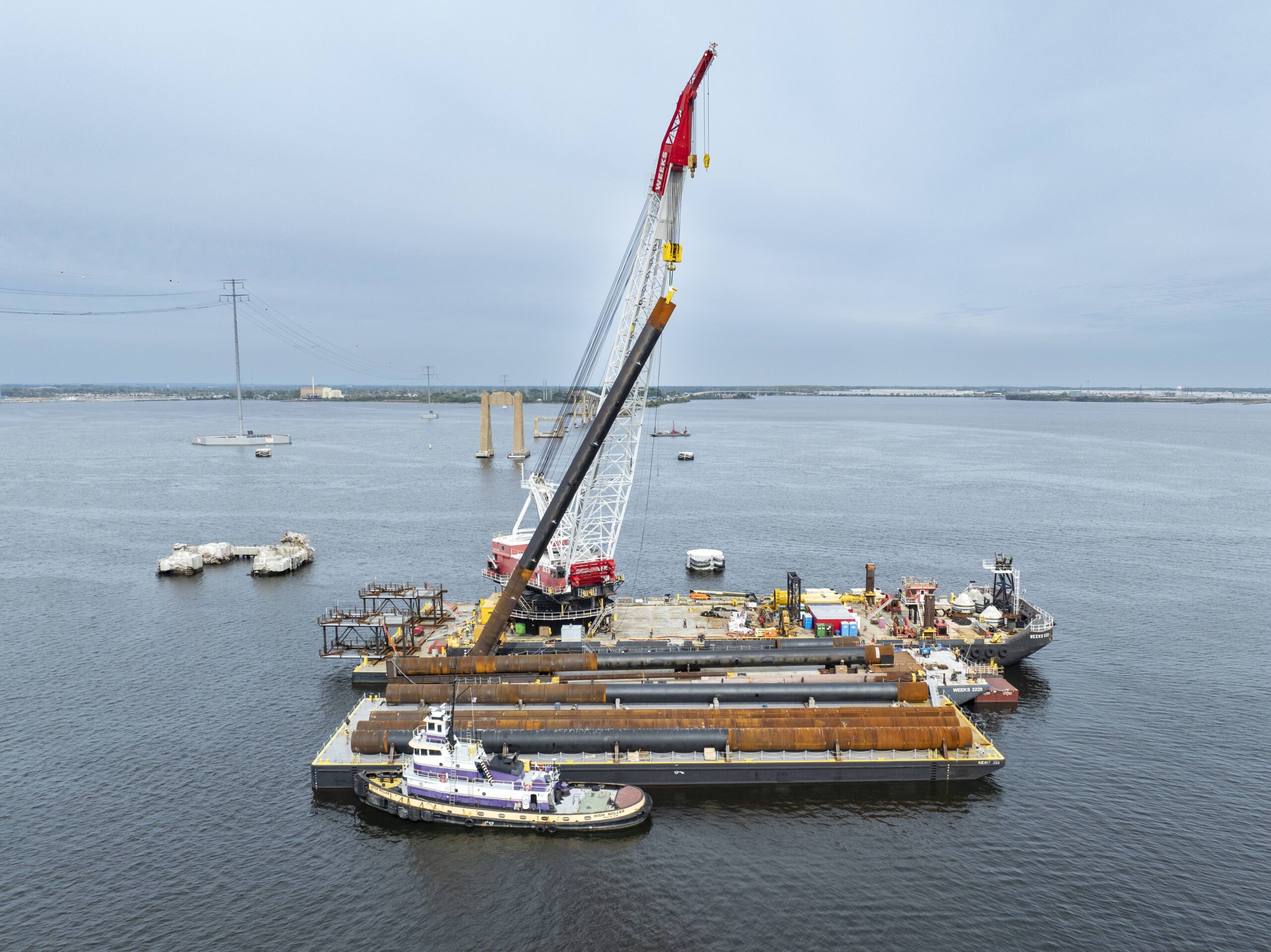 Aerial view of crane and bridge piles on a barge in the water.